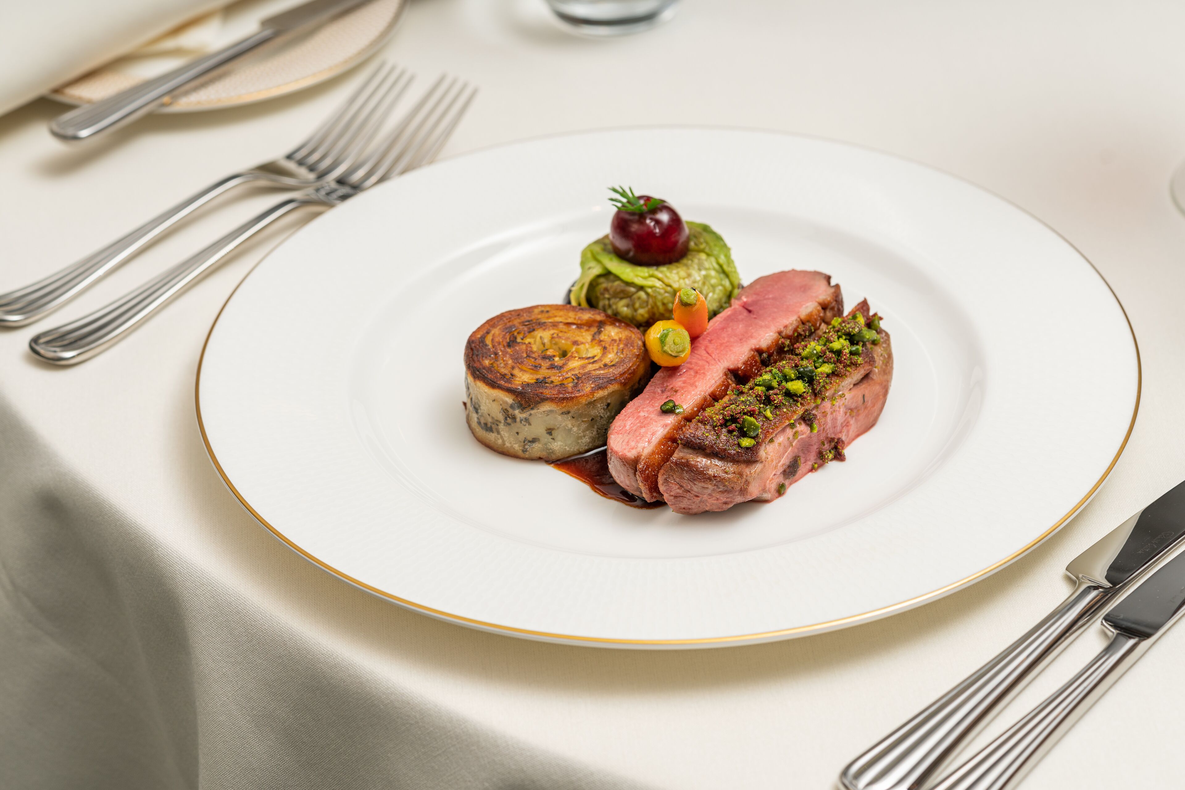 A plate of food with a slice of meat, a small round item, and a cherry on top.