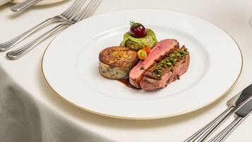 A plate of food with a slice of meat, a small round item, and a cherry on top.