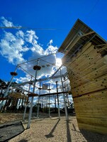 An outdoor adventure park with a climbing wall and various obstacle courses.