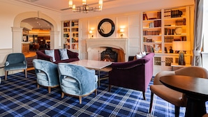 A library with bookshelves, a fireplace, and seating areas.