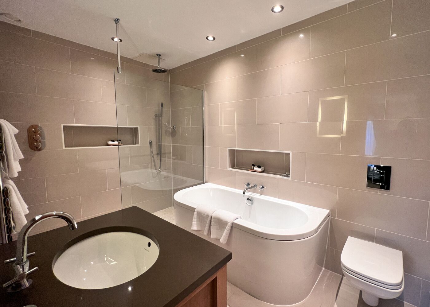 Un baño moderno con ducha acristalada, bañera independiente, lavamanos e inodoro.