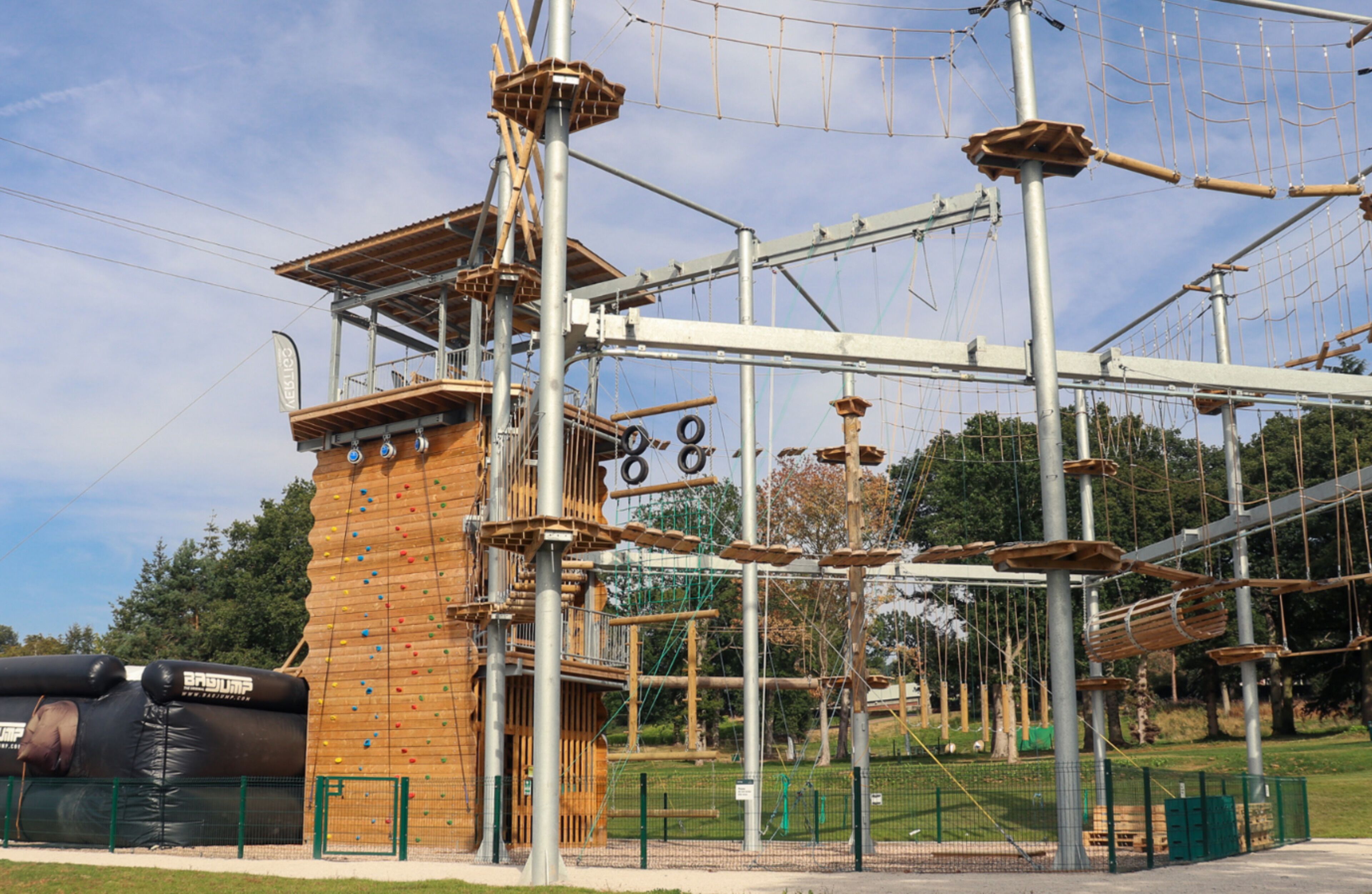 An outdoor adventure park with climbing walls, ropes, and a wooden climbing structure.