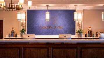 A reception area with a 'Carden Park' sign, two laptops, and a variety of bottles on a counter.