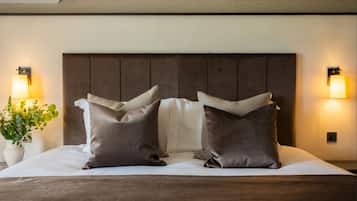 A neatly made bed with a wooden headboard, two pillows, and two wall-mounted lamps on either side.