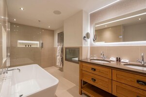 Un baño moderno con una bañera grande, dos lavamanos y un mueble de tocador de madera.