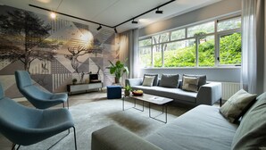 A modern living room with a sofa, two armchairs, a coffee table, and a large window with a view of greenery. - Bilderberg Résidence Groot Heideborgh (Garderen)