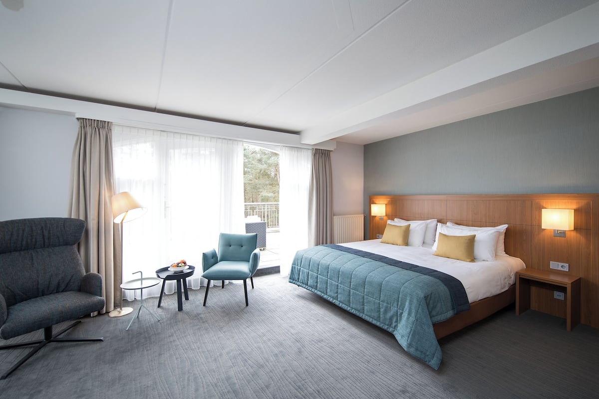 Una habitación de hotel con una cama grande, un sofá, una mesita y una silla.
