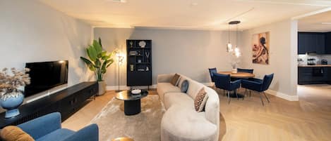 A modern living room with a sofa, chairs, a coffee table, and a TV.