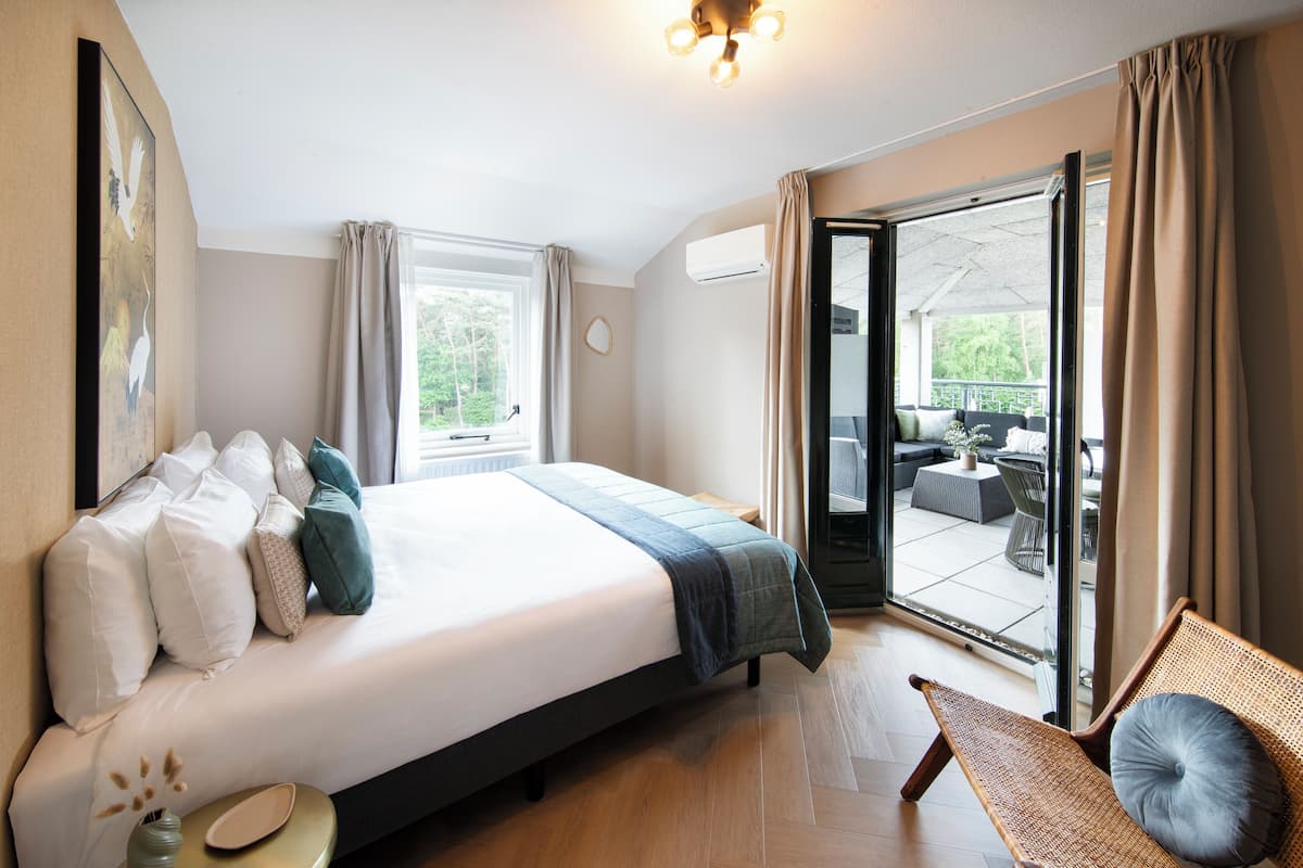 Habitación de hotel con una cama grande, un banco, vistas del patio exterior y una lámpara en el techo.