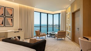 Ein modernes Hotelzimmer mit großem Fenster, einem Bett, einer Sitzecke mit Stühlen, einem kleinen Tisch und einem Kleiderschrank.