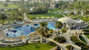 Un resort con una piscina grande, palmeras y vista al mar.
