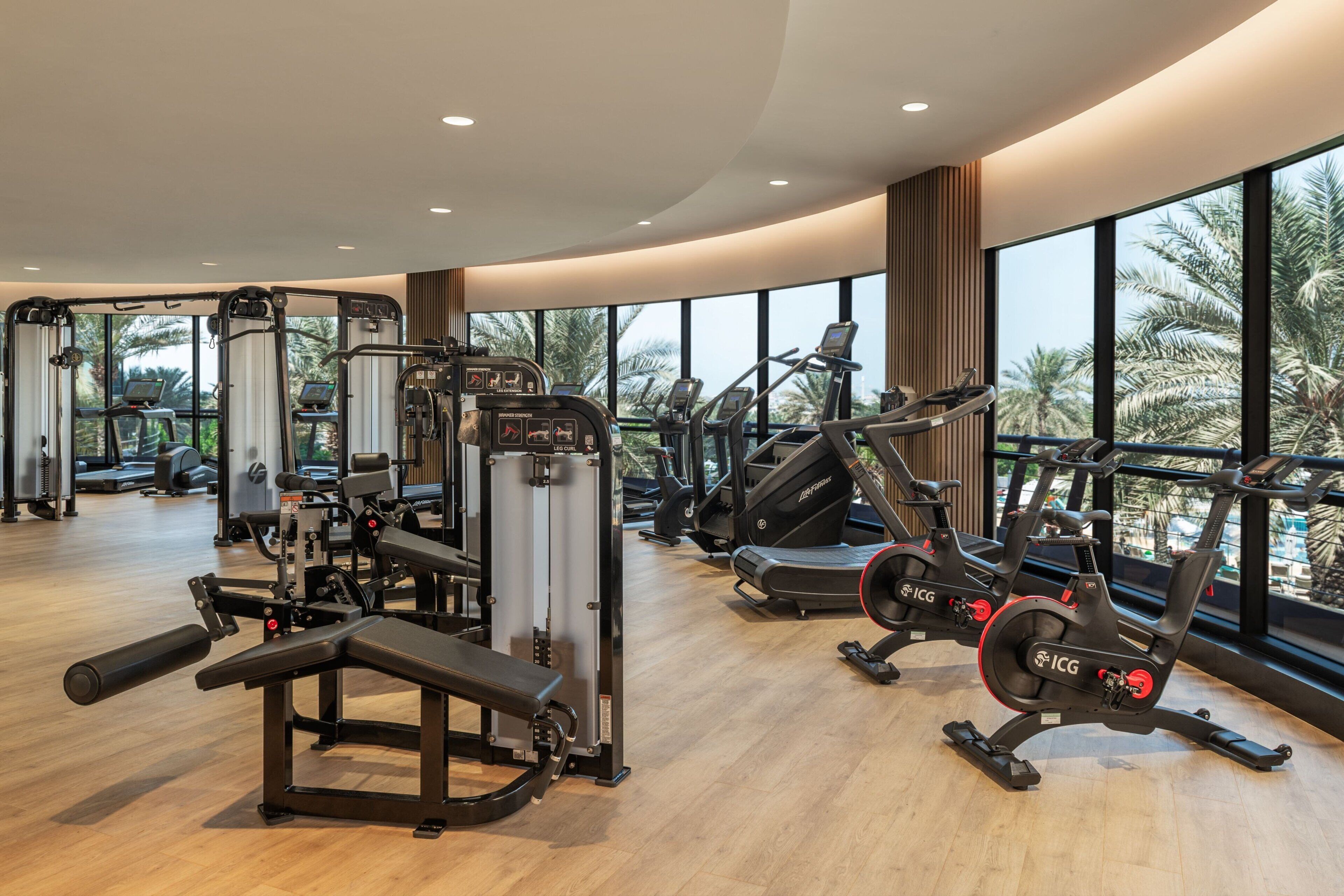 Ein Fitnessstudio mit Cardiogeräten, Kraftstationen und einer Langhantelbank.