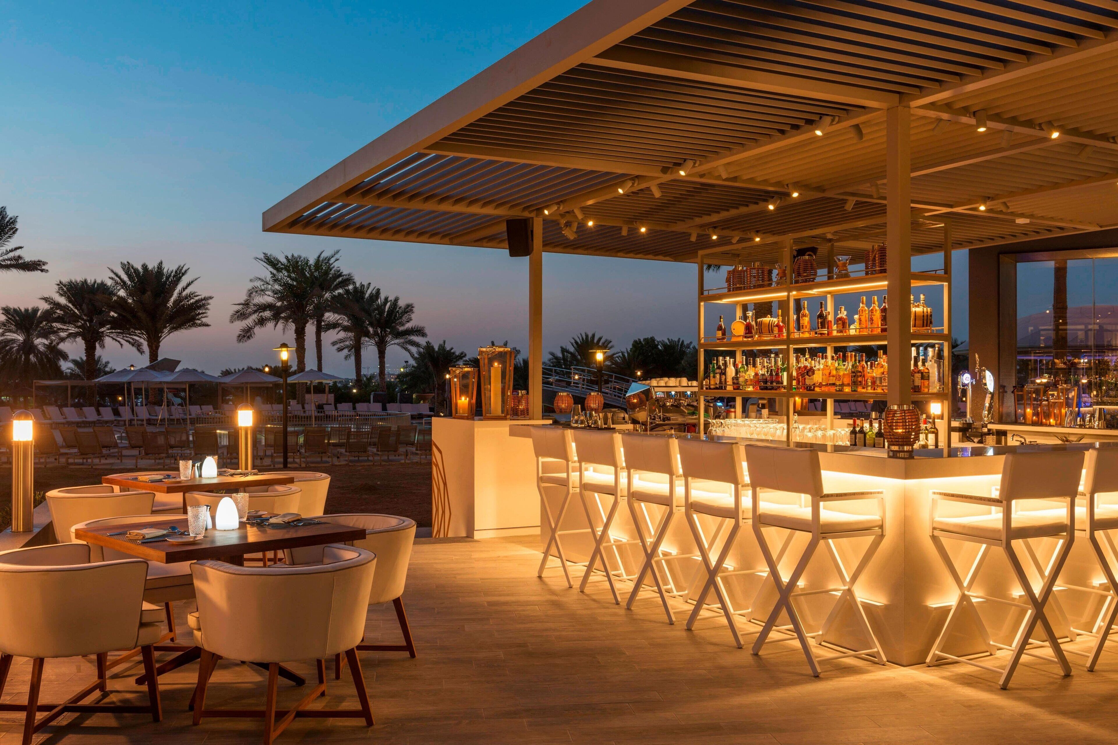 An outdoor bar area with seating and a bar stocked with bottles.