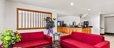 A living room with red sofas, a small table, and a potted plant.