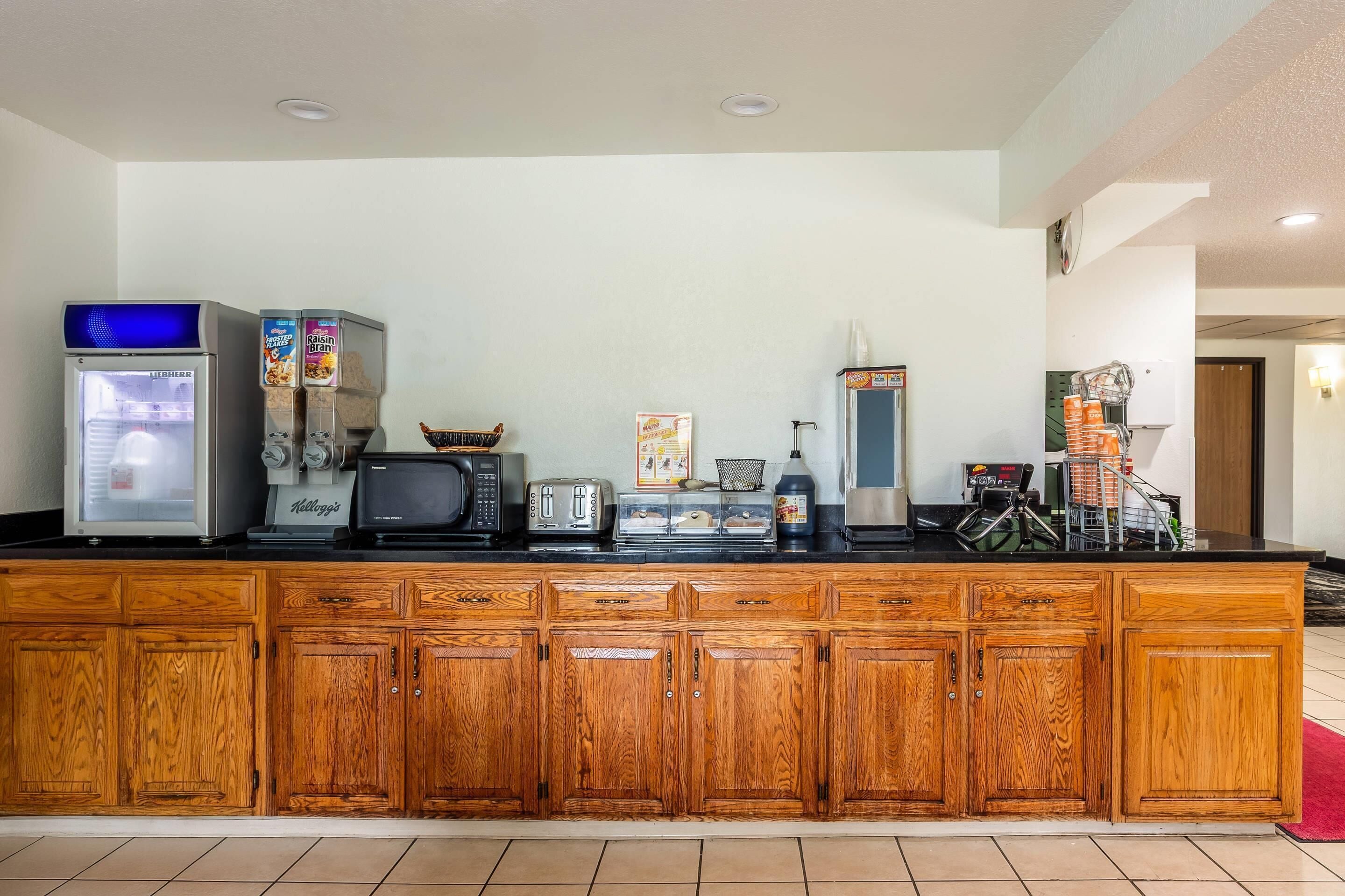 A kitchenette with a refrigerator, microwave, toaster, coffee maker, and cereal boxes.