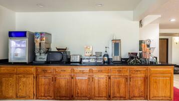 A kitchenette with a refrigerator, microwave, toaster, coffee maker, and cereal boxes.