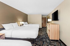 A hotel room with two beds, a flat-screen TV, a wooden dresser, and a patterned carpet.
