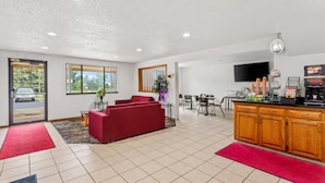 A modern hotel lobby with a red sofa, a wooden bar area, and a dining space.
