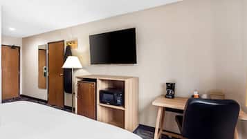 A hotel room with a bed, a desk with a chair, a television, a microwave, and a coffee maker.