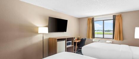 A hotel room with two beds, a desk with a chair, a flat-screen TV, and a window with curtains.