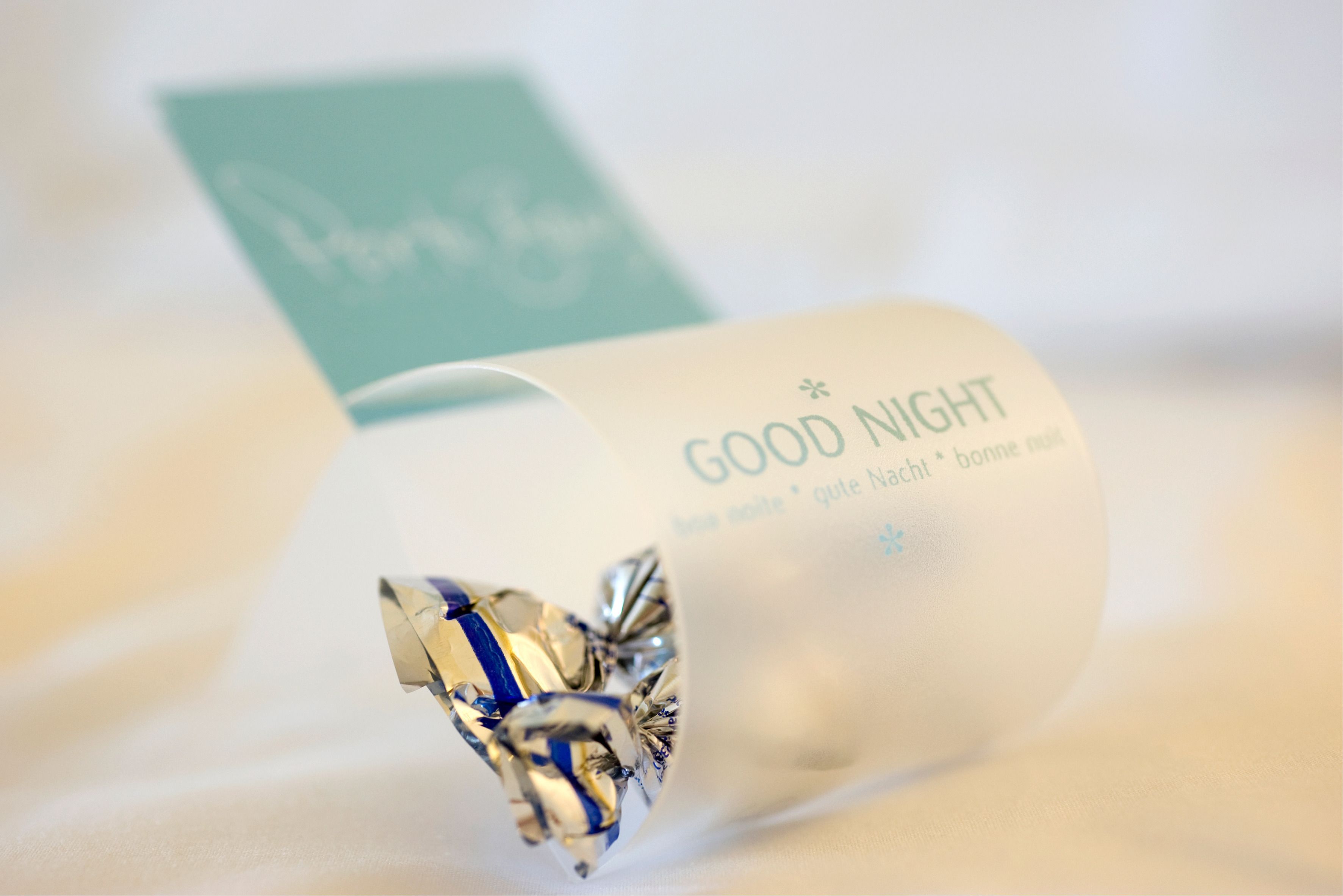 Un objet enroulé sur lequel est inscrit « BONNE NUIT » et une petite carte avec un logo.