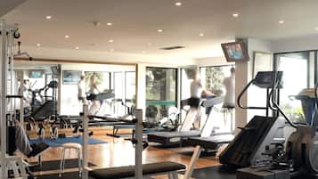 Un gimnasio con cintas de correr, máquinas de pesas y colchonetas de ejercicio.