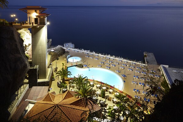 A resort with a large pool, beach area, and a high vantage point overlooking the sea.