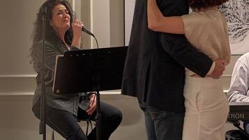 A person playing a piano in a room with a large abstract painting on the wall.