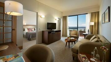 A hotel room with a bed, a TV, a sofa, a coffee table, and a balcony with a view.