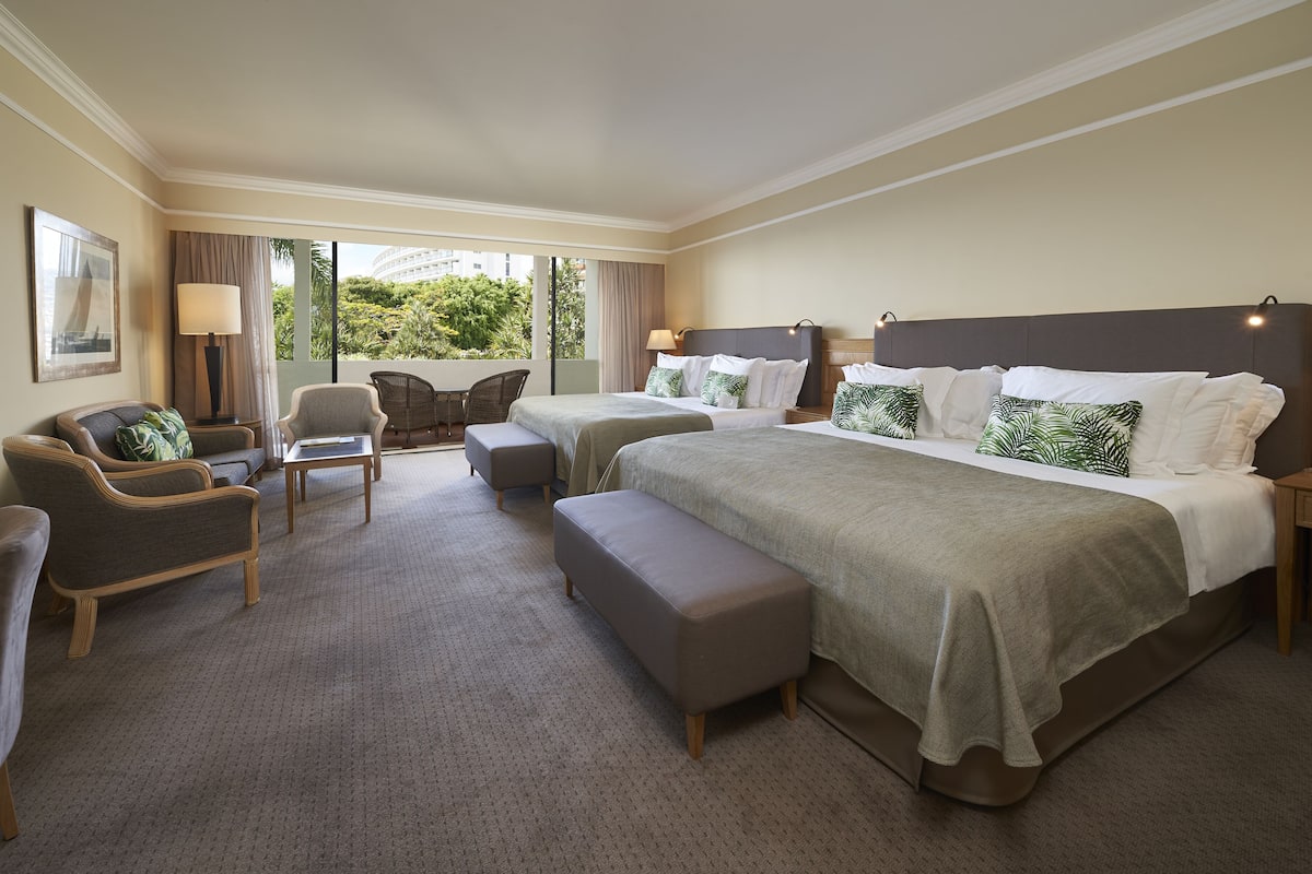 Habitación de hotel con dos camas, un sofá, una silla y una mesita.