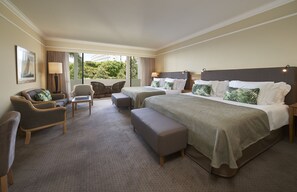 A hotel room with two beds, a sofa, a chair, and a small table.