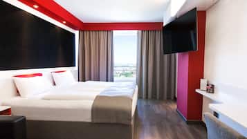 A modern hotel room with a large bed, a TV, and a balcony view.