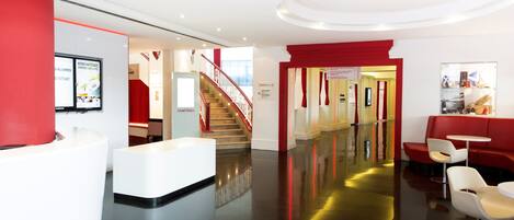 Una hall d'albergo con reception, una scala e zone relax.