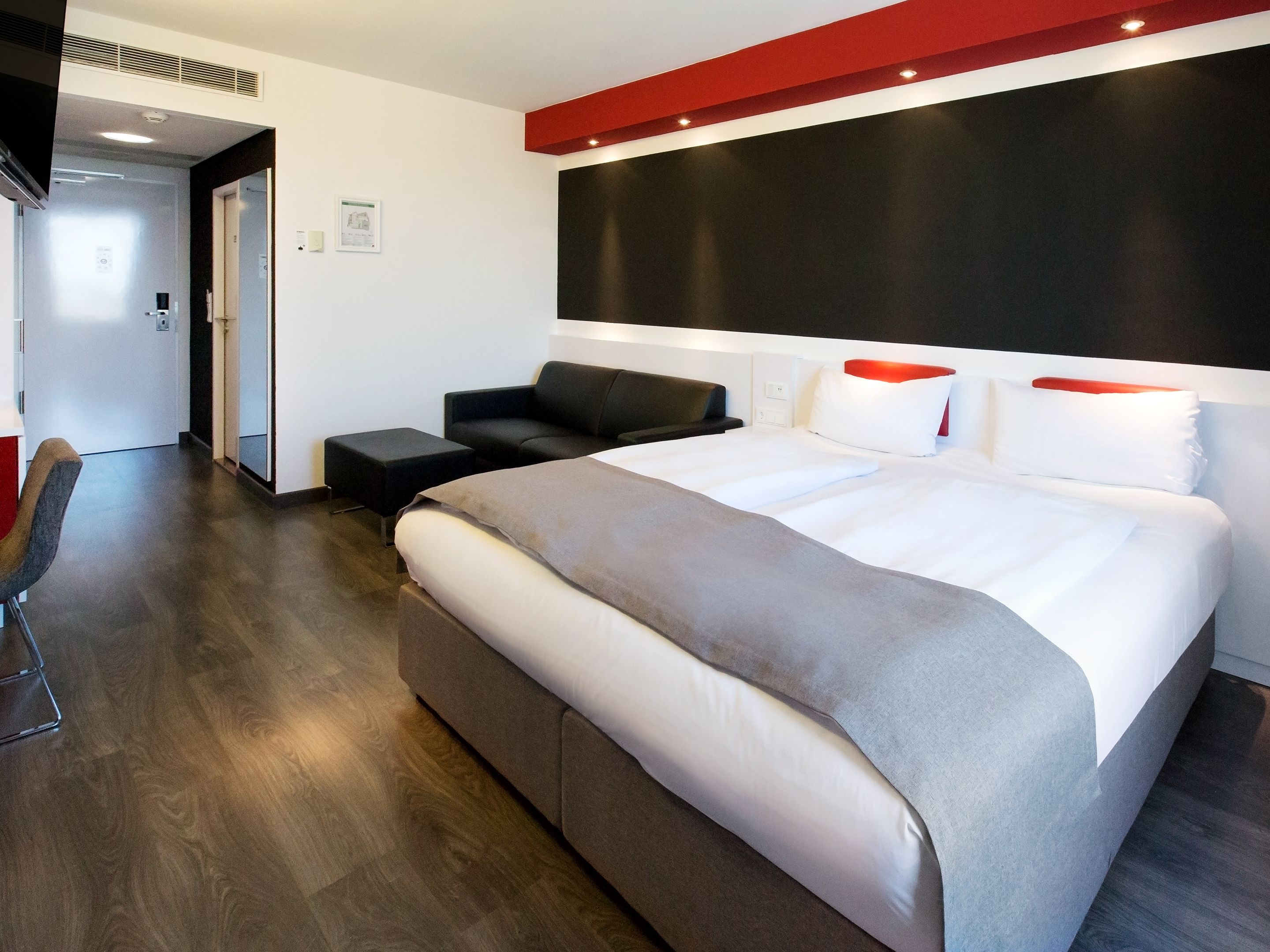 Una habitación de hotel moderna con una cama grande, un sofá y un escritorio.