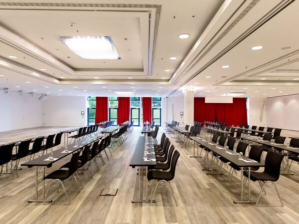A conference room with long tables, black chairs, and a modern ceiling design.