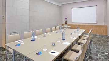 A conference room with a long table, chairs, a projector screen, and a water dispenser.