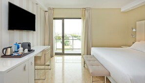 A hotel room with a bed, a desk with a flat-screen TV, a coffee maker, and a window with curtains. - NH Ciudad de Zaragoza (Zaragoza)