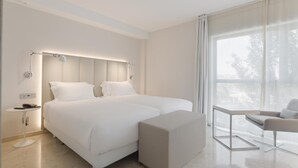 Un dormitorio moderno con una cama grande, mesitas de noche, una silla y una ventana con cortinas.