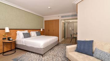 Una habitación de hotel con cama, mesita de noche, lámpara y un sofá.