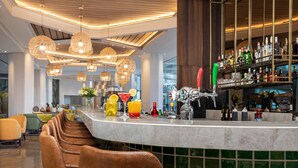 A bar area with a marble countertop, hanging wicker chandeliers, and a variety of bottles and glasses.