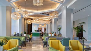 A spacious lobby with multiple seating areas, a reception desk, and decorative lighting fixtures.