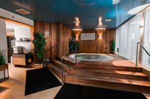 A spa area with a wooden floor, a hot tub, and a staircase leading to a shower area.