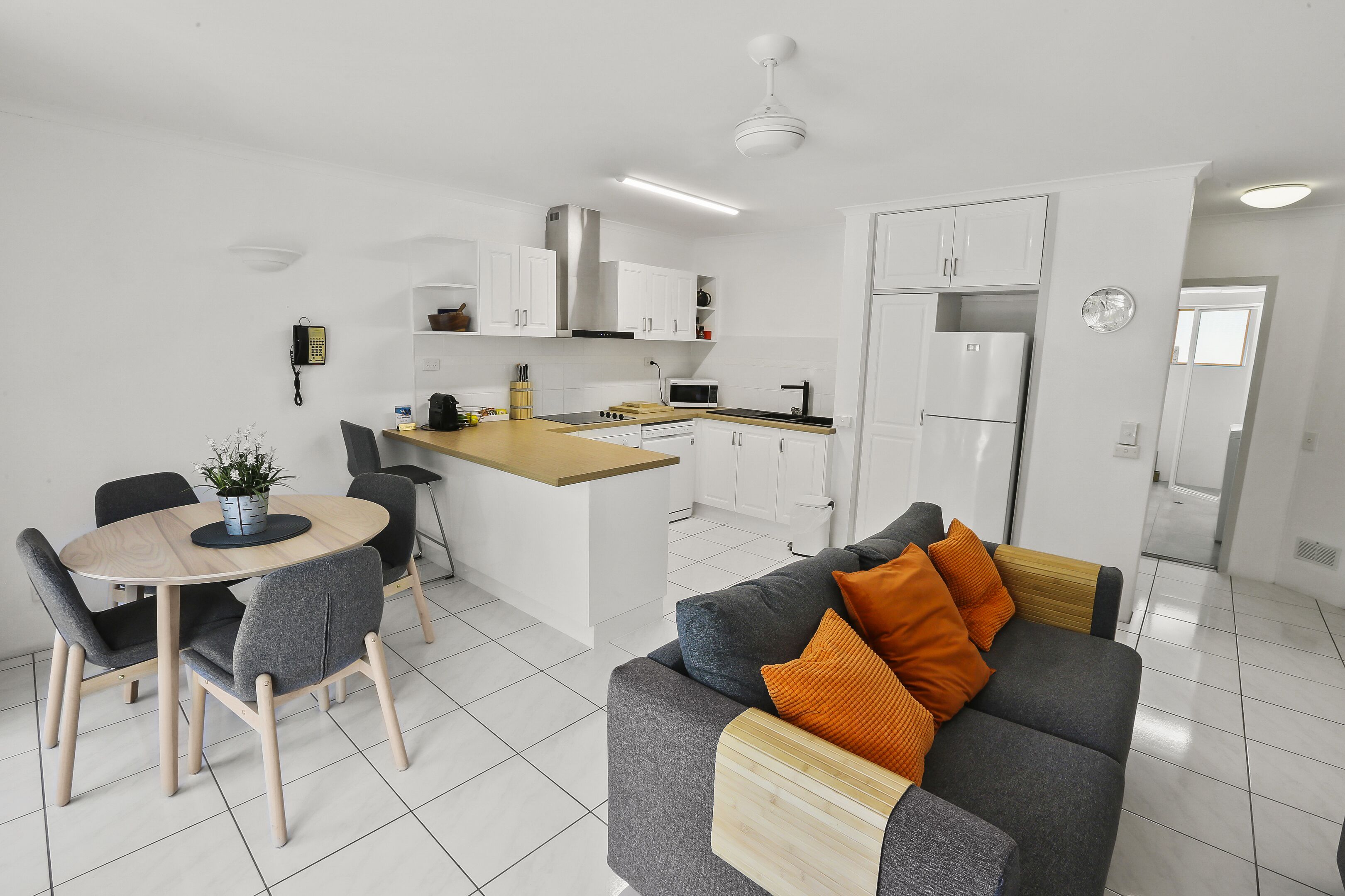 A modern kitchen with white cabinets, a central island, and a dining area with a round table and chairs.
