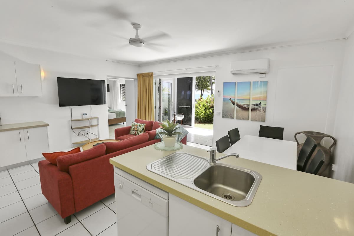 Una cocina moderna con una isla central, un comedor y una sala de estar con un sofá rojo.