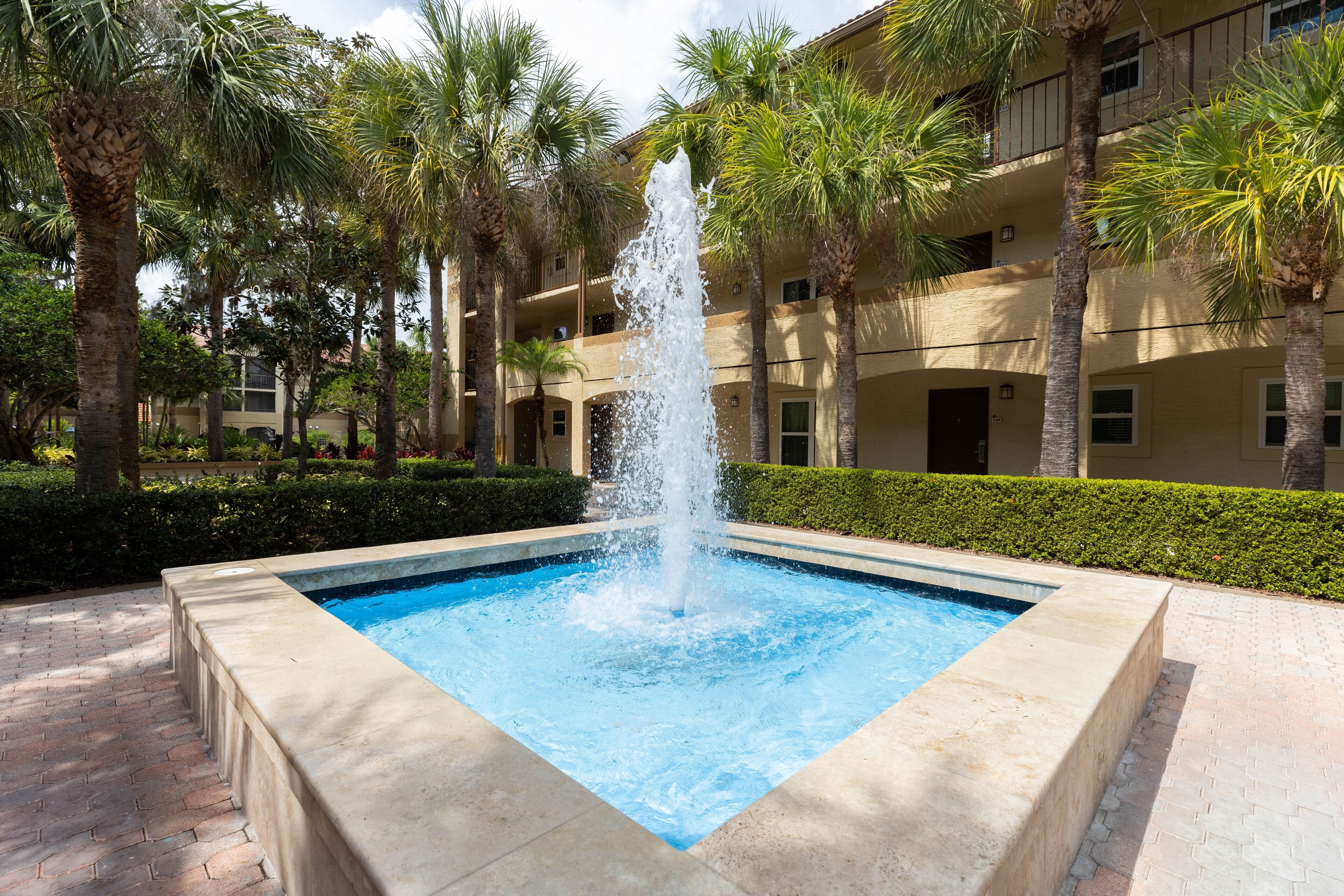 A rectangular pool with a central water jet feature, surrounded by a brick border.