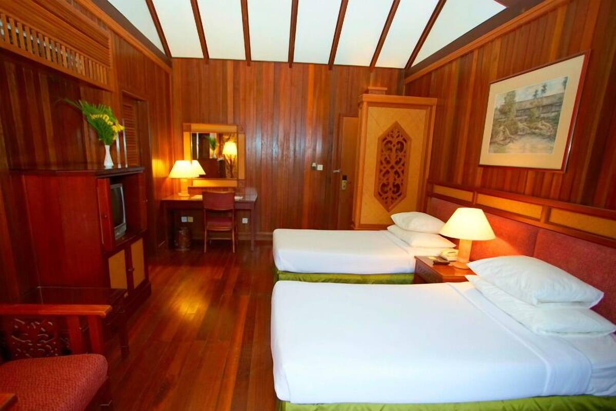 Habitación de hotel con dos camas, un escritorio con silla, un televisor y un cuadro en la pared.
