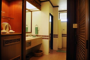 Une salle de bain d’hôtel avec un meuble-lavabo en bois, un évier, un miroir et un espace douche.