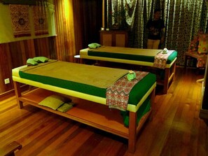 Une chambre avec deux lits en bois, chacun recouvert d’une couverture verte et agrémenté d’un coussin à motifs.