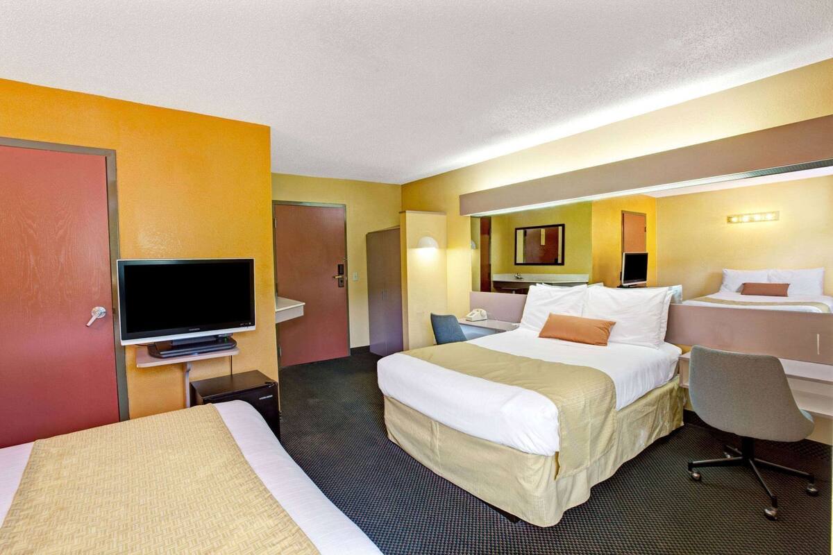 Una habitación de hotel con cama, escritorio, silla, televisor y baño.