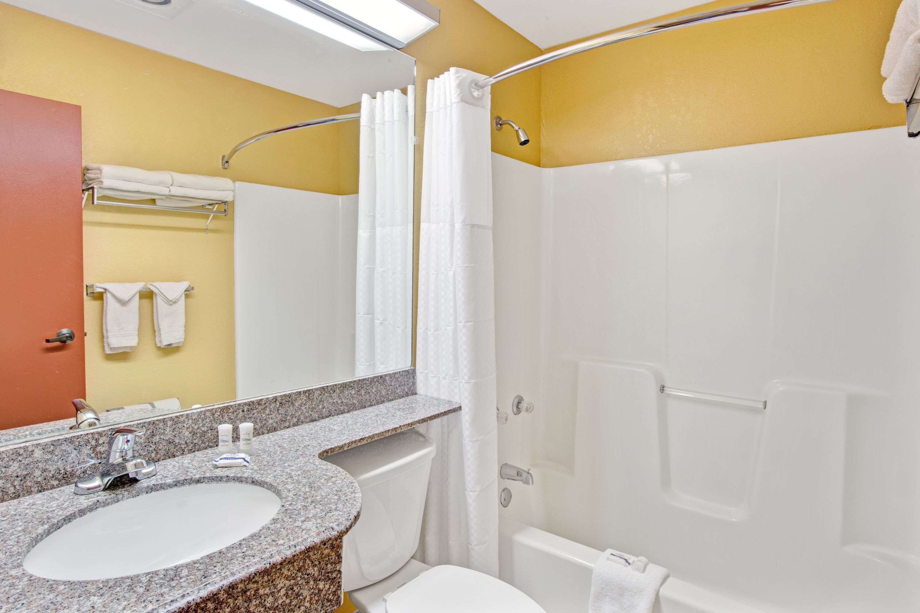 A bathroom with a granite sink, white toilet, and a shower with a glass door.